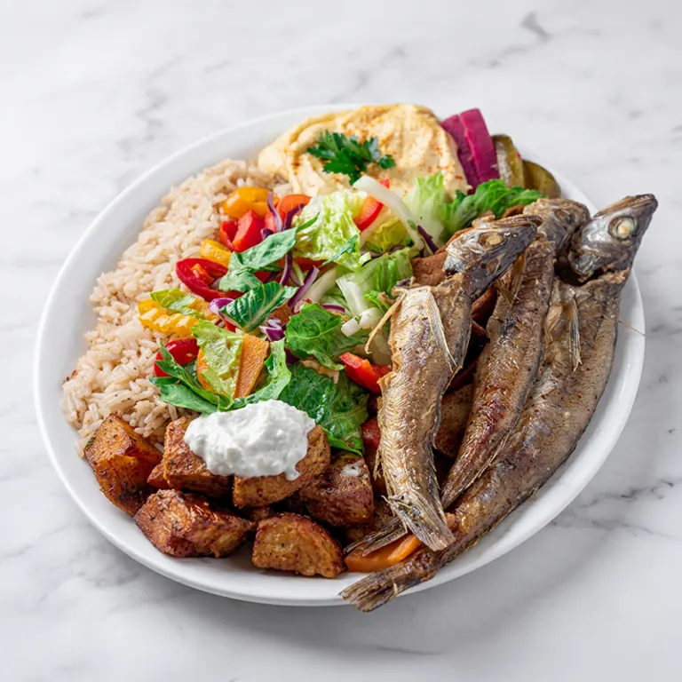 Fried whiting fish plate Ottawa with rice, roasted potatoes, salad and hummus